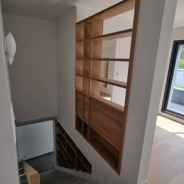 Aménagement de bibliothèque en bois massif sur mesure encastré dans un escalier à  